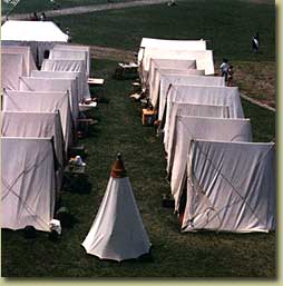 Two rows of small tents with a bell tent in the center