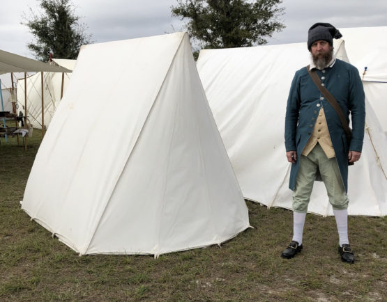 man standing next to the back of a tent