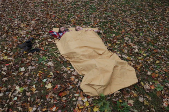 Two adults laying on the ground in an extra wide bed roll