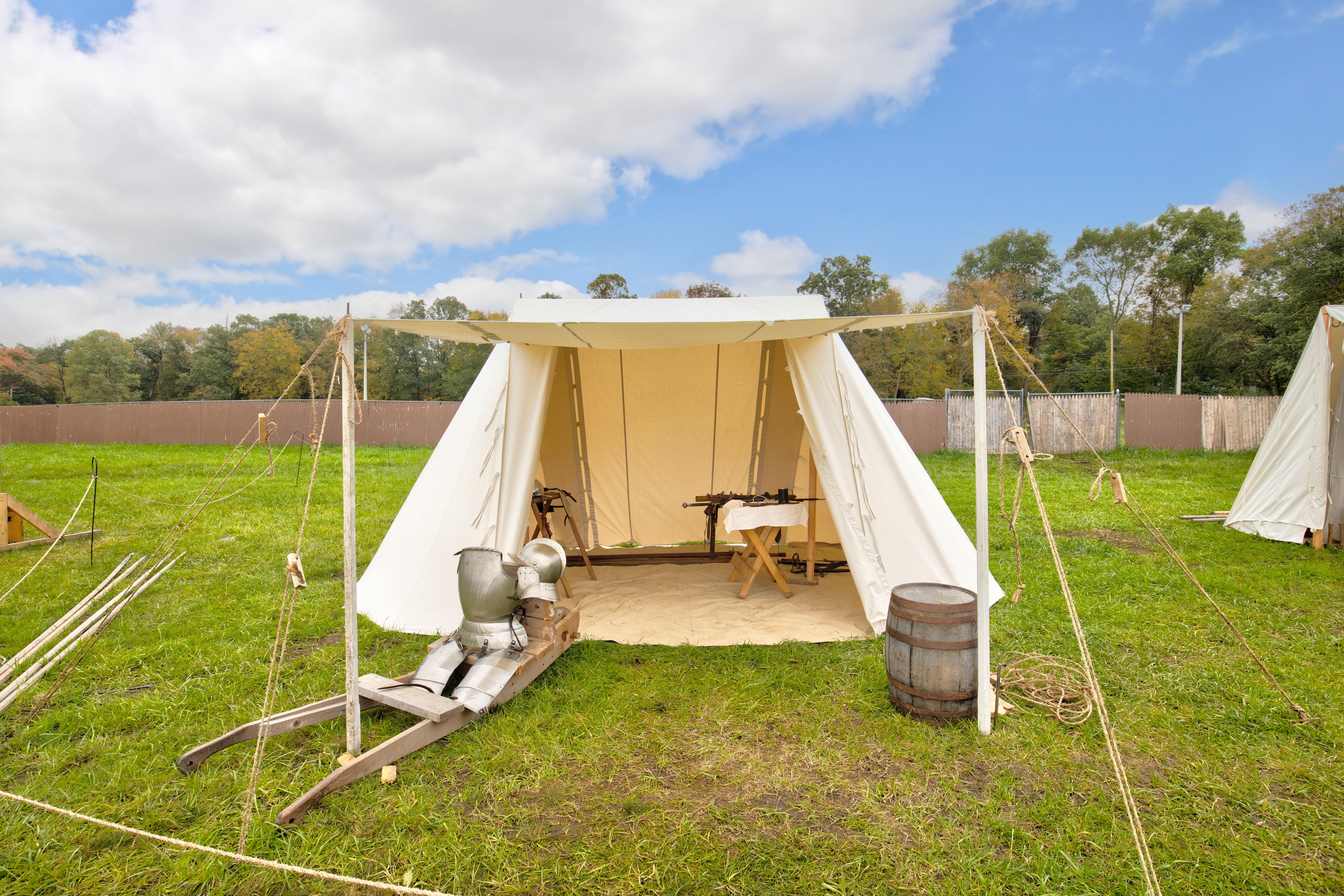 white tent in a field with a fence behind