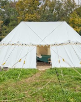 large round ended white canvas tent in a field with trees behind