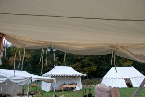 white camvas tent flap tied up with three tents in the background