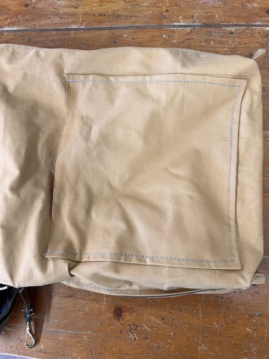 A satchel bag turned inside out to show a large pouch pocket found within.