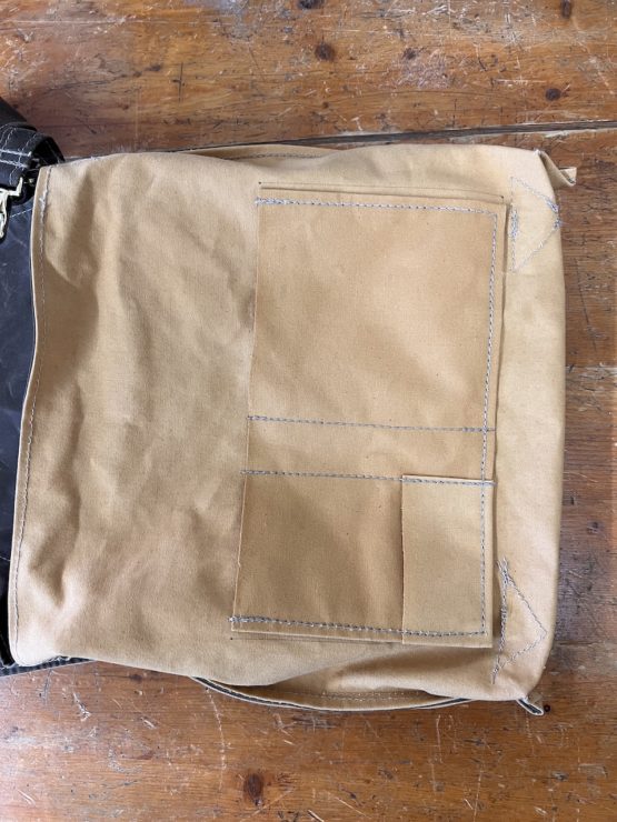 A satchel bag turned inside out to show a large pouch pocket found within. It is divided into differently-sized sections by sticthing.
