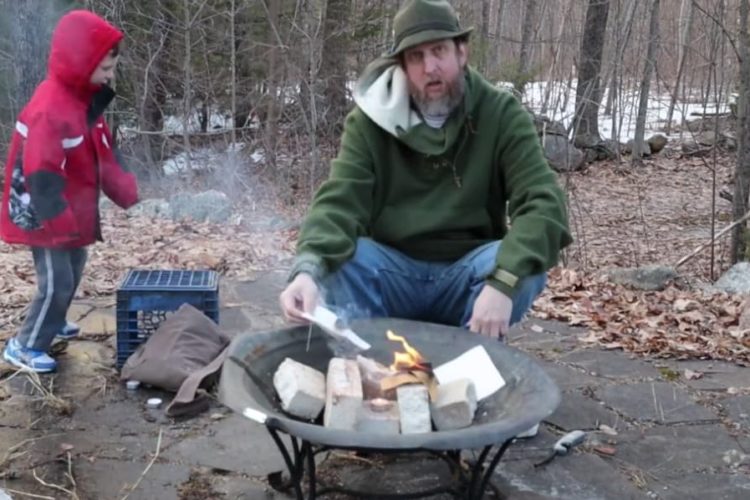 Man and boy by fire pit, man lighting canvas on fire