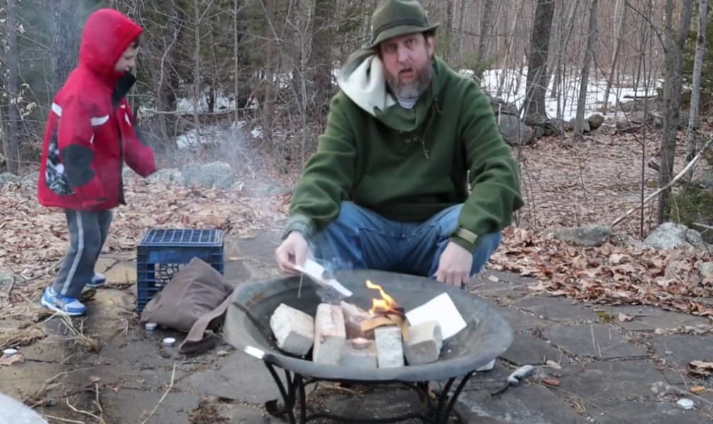 Man and boy by fire pit, man lighting canvas on fire