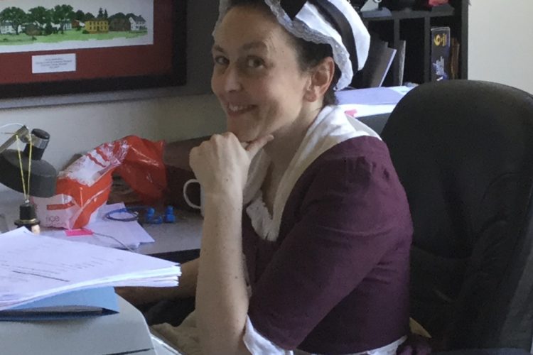 Woman in colonial clothes at a computer desk