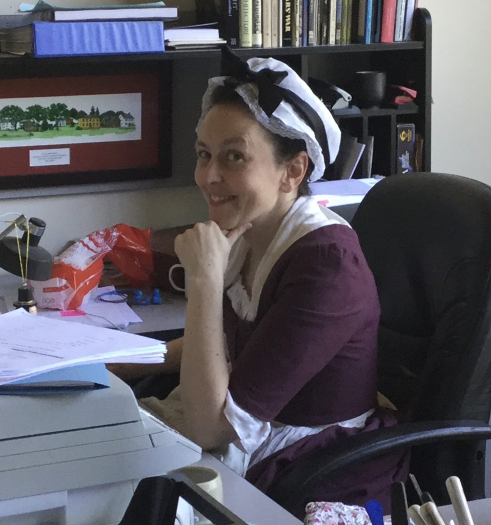 Woman in colonial clothes at a computer desk