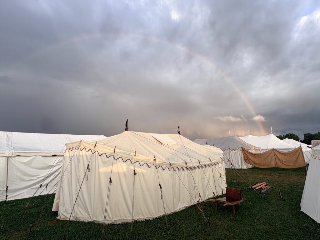 fancy tent under a gray sky with a rainbow.