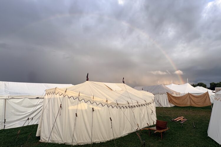 fancy tent under a gray sky with a rainbow.